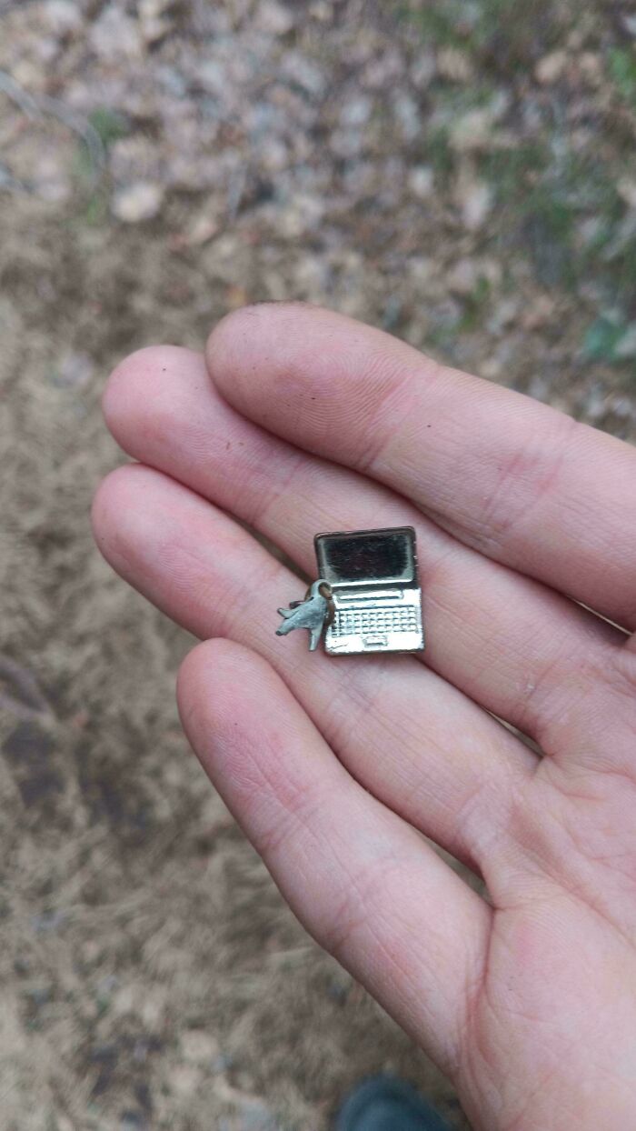 Tiny laptop charm held between fingers, showing a completely unremarkable photo with entertaining detail outdoors.
