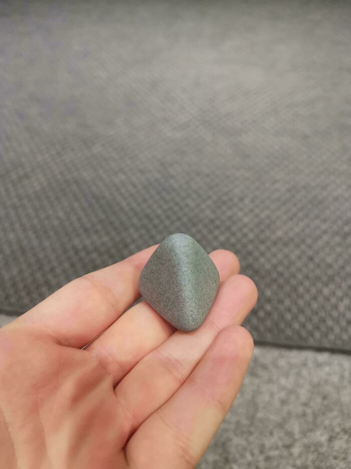 Hand holding a small, smooth, unremarkable stone, part of a collection of entertaining unremarkable photos.