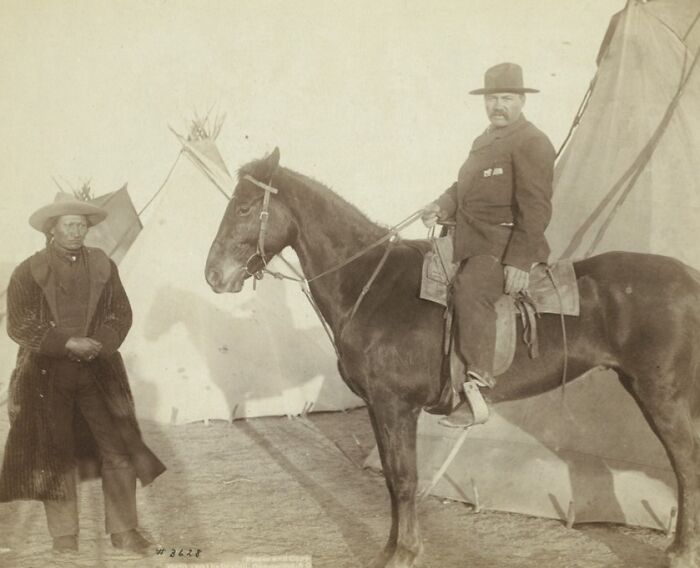 Authentic 1800s photo of a cowboy on horseback and a Native American standing outside traditional teepees.