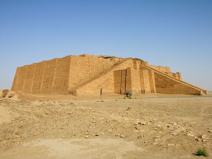Ancient man-made structure with large stepped brick walls in an arid desert landscape under a clear blue sky.