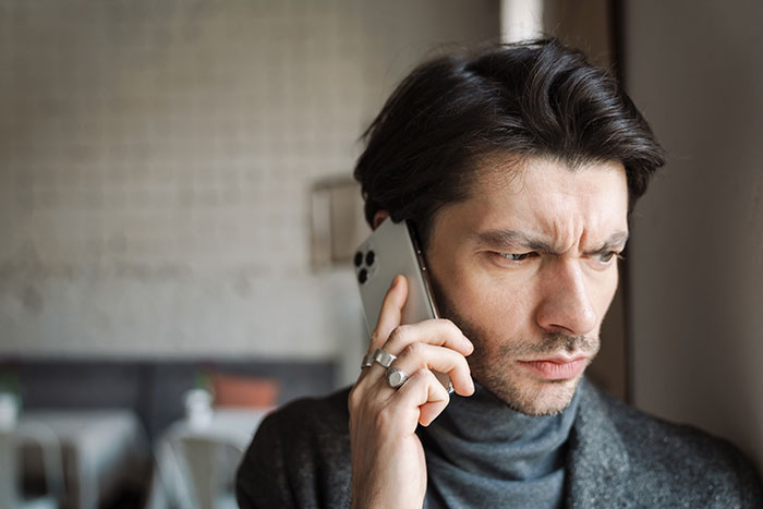 Man on phone looking concerned, wearing a dark sweater, related to woman dumping boyfriend over heiress dispute. Man on phone looking concerned, wearing a dark sweater, related to woman dumping boyfriend over heiress dispute.