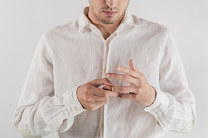 Man in a white shirt removes a wedding ring, reflecting tension in marriage. Man in a white shirt removes a wedding ring, reflecting tension in marriage.