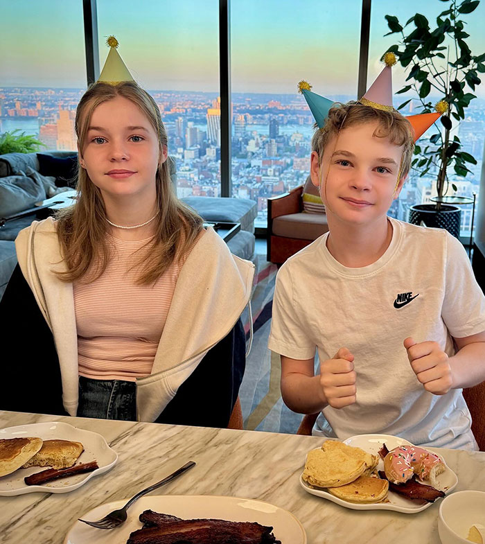 Two children in party hats sitting at a table with breakfast, enjoying a scenic view, highlighting "carbon copy" theme. Two children in party hats sitting at a table with breakfast, enjoying a scenic view, highlighting "carbon copy" theme.