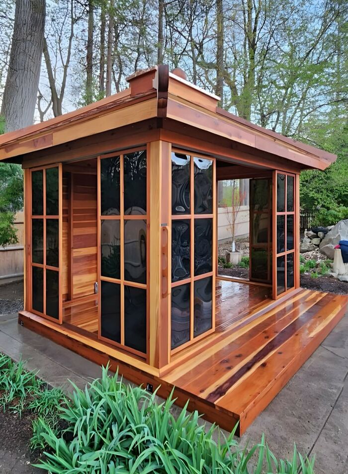 Wooden outdoor gazebo with glass panels showcasing beautifully crafted woodworking projects in a natural garden setting.