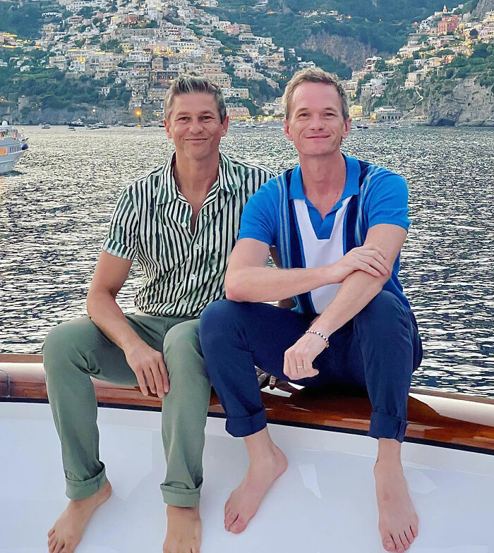 Two men sitting on a boat in front of a scenic coastal backdrop, enjoying a trip. Two men sitting on a boat in front of a scenic coastal backdrop, enjoying a trip.