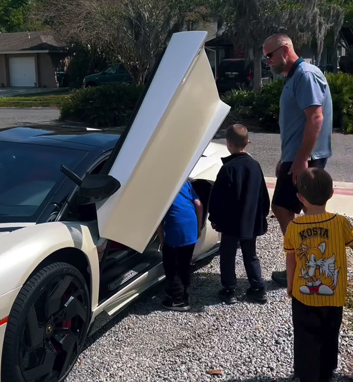 Local sports car lovers surprise boy on his birthday, gathered around an open door of a sleek sports car. Local sports car lovers surprise boy on his birthday, gathered around an open door of a sleek sports car.