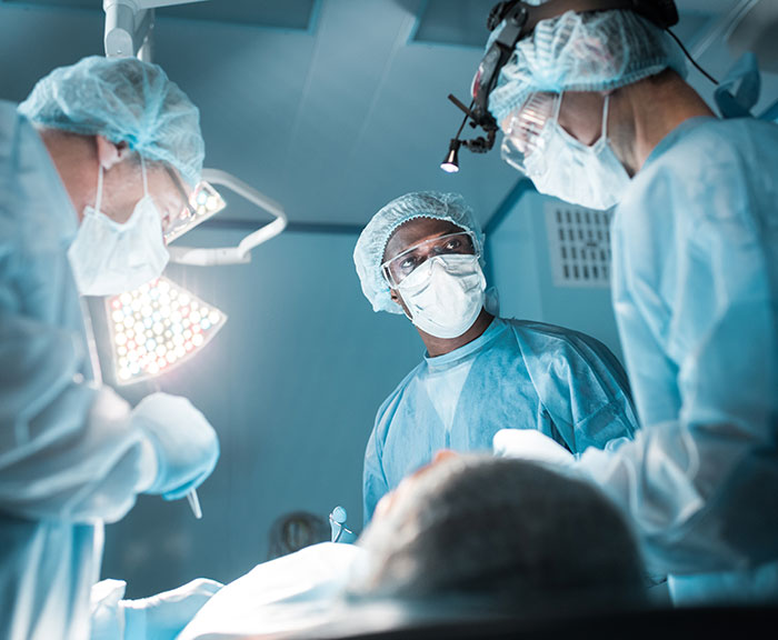 Surgeons in an operating room performing a medical procedure in a clinical setting. Surgeons in an operating room performing a medical procedure in a clinical setting.