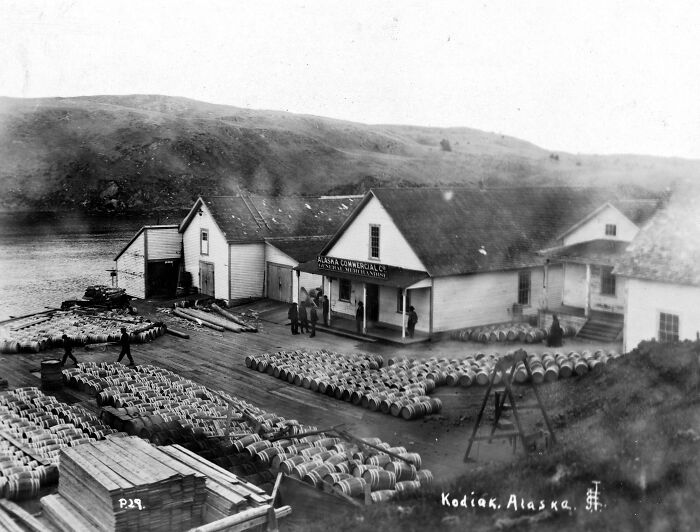 Historic waterfront scene in America from 100 years ago showing barrels and buildings at Kodiak, Alaska port.