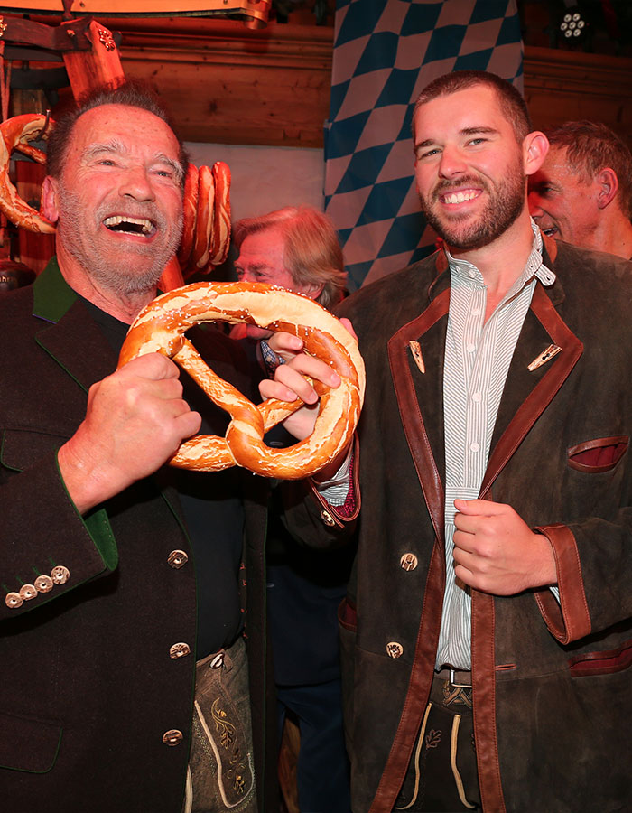 Two people in traditional attire holding a large pretzel, celebrating impressive weight loss transformation at an event. Two people in traditional attire holding a large pretzel, celebrating impressive weight loss transformation at an event.