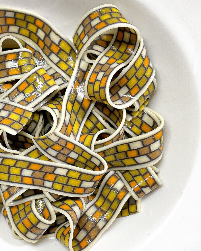 Handcrafted pasta with vibrant mosaic patterns in a white bowl, showcasing culinary artistry.