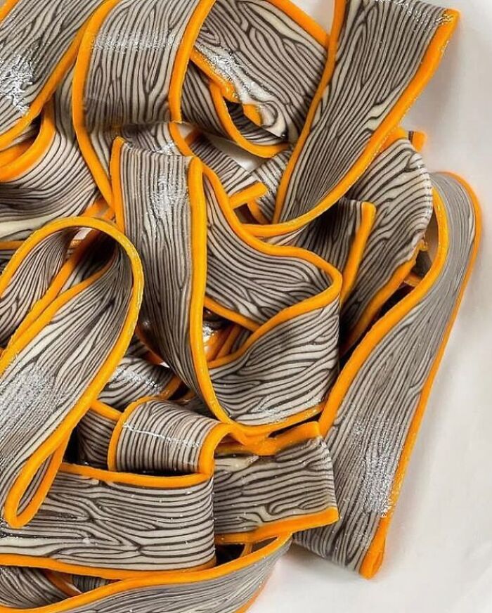 Handcrafted pasta with woodgrain pattern and vibrant orange edges.