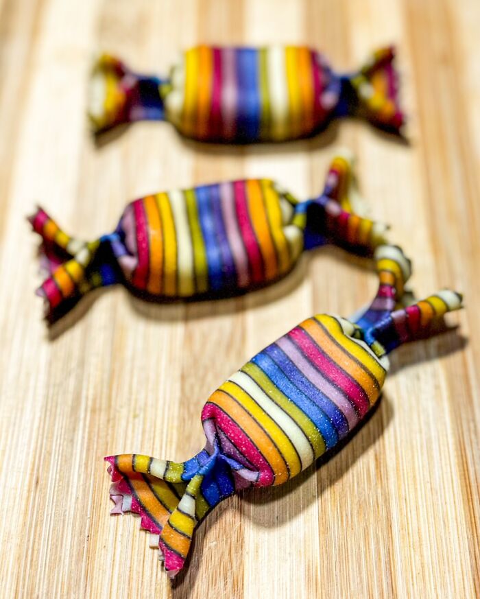 Colorful handcrafted pasta with vibrant stripes, resembling candy, on a wooden board by a culinary artist.
