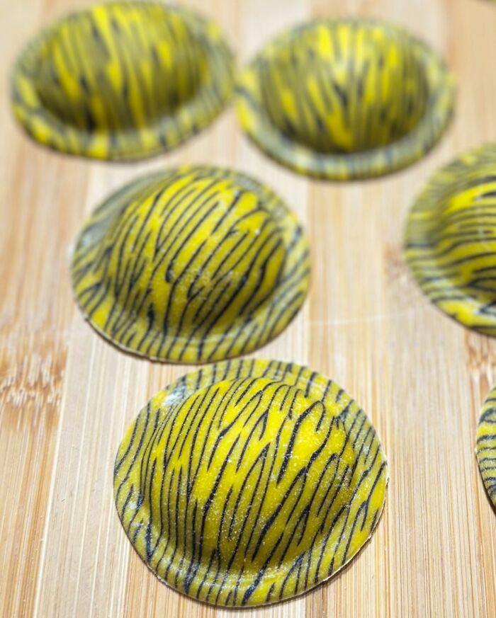 Colorful handcrafted pasta with black stripes on a wooden board, showcasing unique culinary artistry.