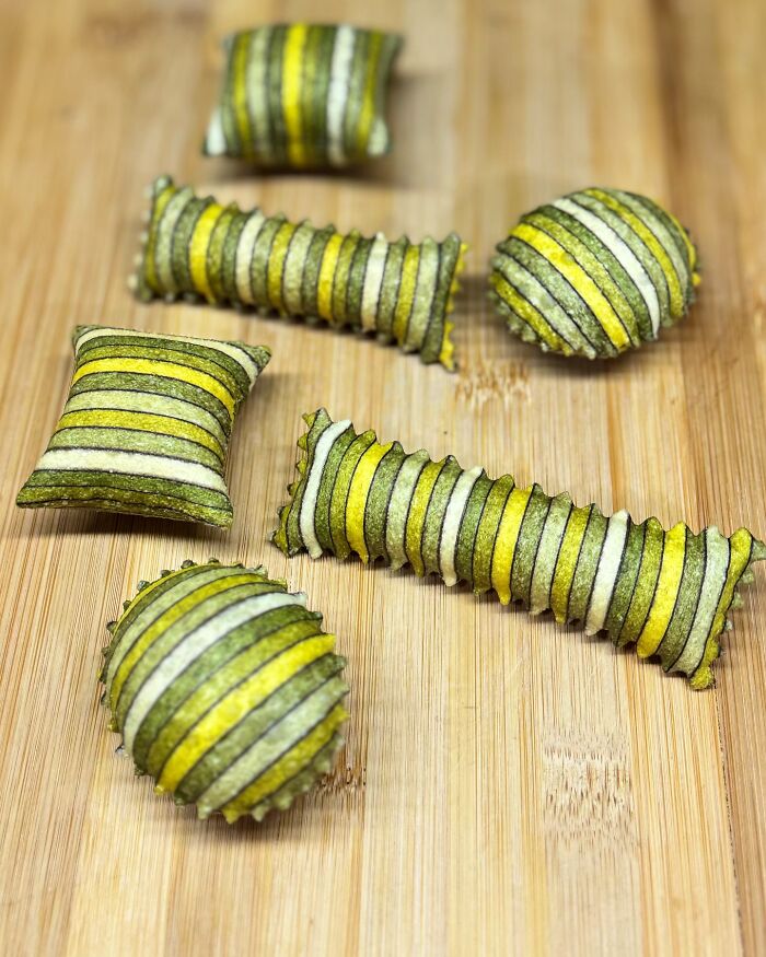 Handcrafted pasta in stripes of green, yellow, and white, showcasing a chef's colorful and patterned culinary artistry.