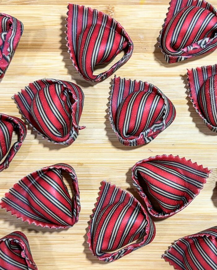 Striped handcrafted pasta on a wooden surface, showcasing colorful patterns by a culinary artist chef.