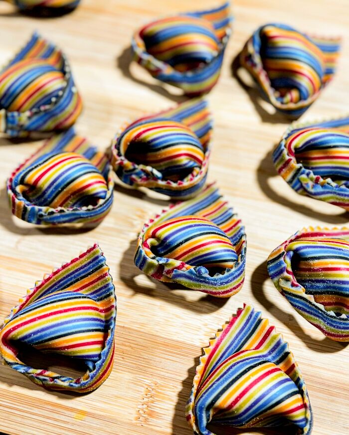 Handcrafted pasta with colorful patterns on a wooden board, showcasing culinary artistry.