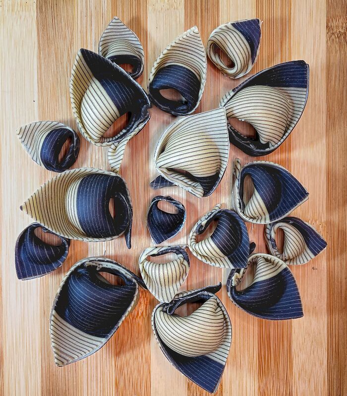 Handcrafted pasta with intricate blue and beige patterns on a wooden surface, created by a culinary artist chef.