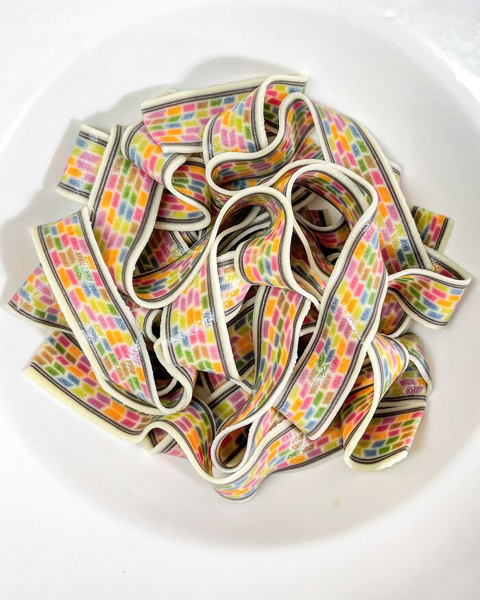 Colorful handcrafted pasta with vibrant patterns arranged in a white bowl.
