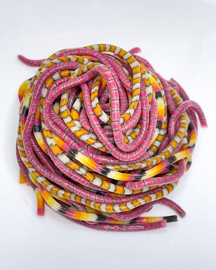 Colorful handcrafted pasta with pink, yellow, and white stripes, showcasing culinary artistry.
