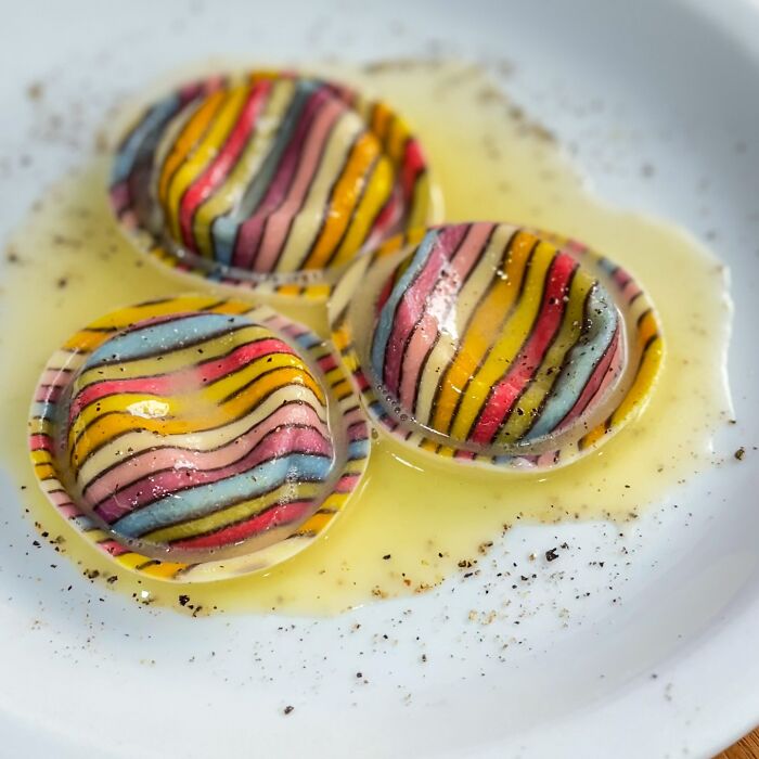 Colorful handcrafted pasta with striped patterns on a plate, showcasing culinary artistry.