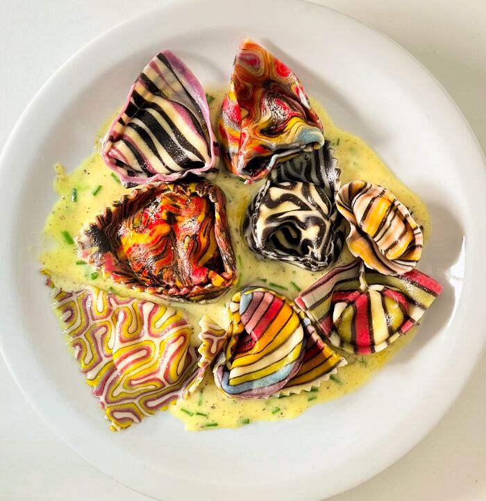 Colorful, patterned handcrafted pasta on a plate with creamy sauce, showcasing culinary artistry and design.