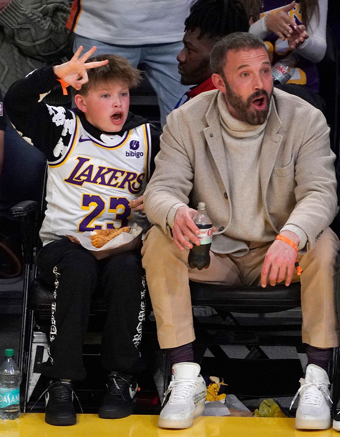 Man with beard and child in Lakers jersey at basketball game, promoting work ethics in rich kids. Man with beard and child in Lakers jersey at basketball game, promoting work ethics in rich kids.