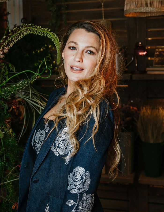 Woman wearing a floral patterned jacket, standing amid greenery. Woman wearing a floral patterned jacket, standing amid greenery.