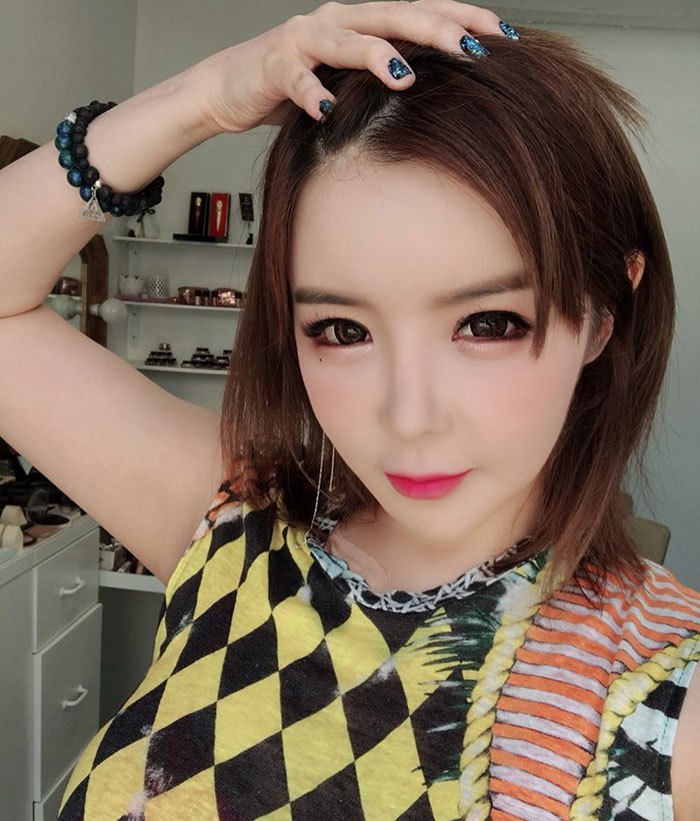 K-Pop star posing indoors with hand on head, amid plastic surgery rumors. K-Pop star posing indoors with hand on head, amid plastic surgery rumors.