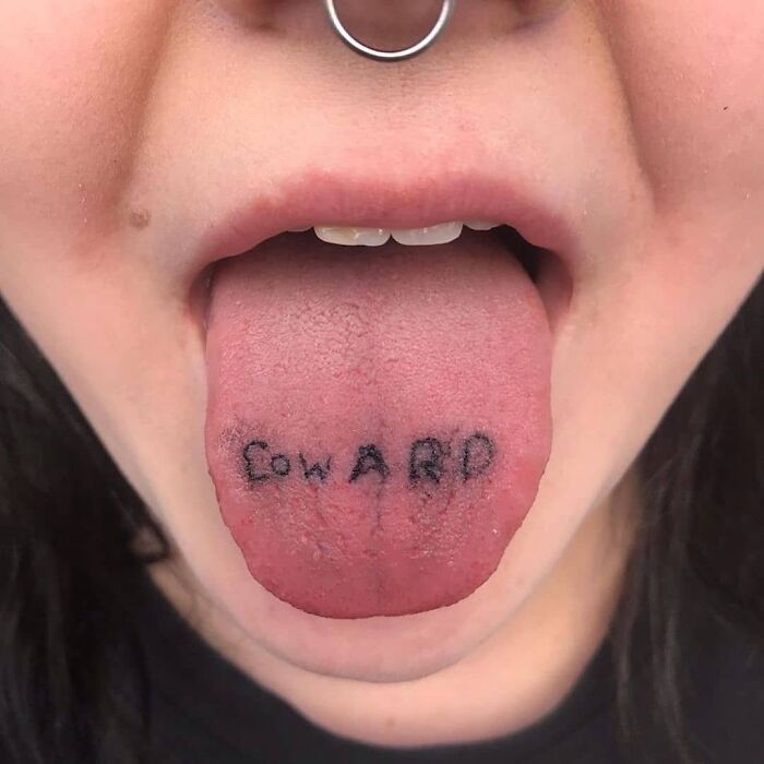 Bad tattoo of the word "coward" inked on a person's tongue.