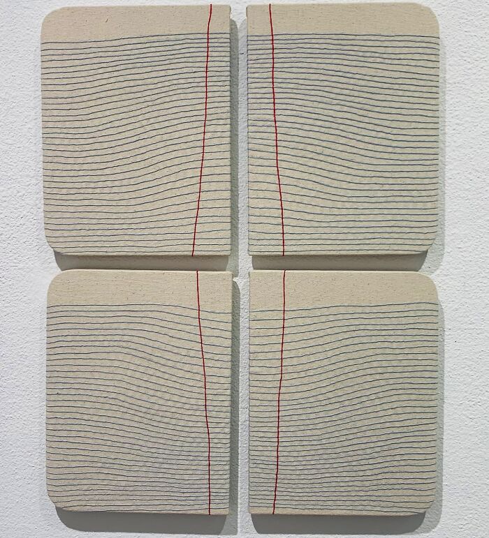 Fabric art resembling notebook pages with embroidered lines.