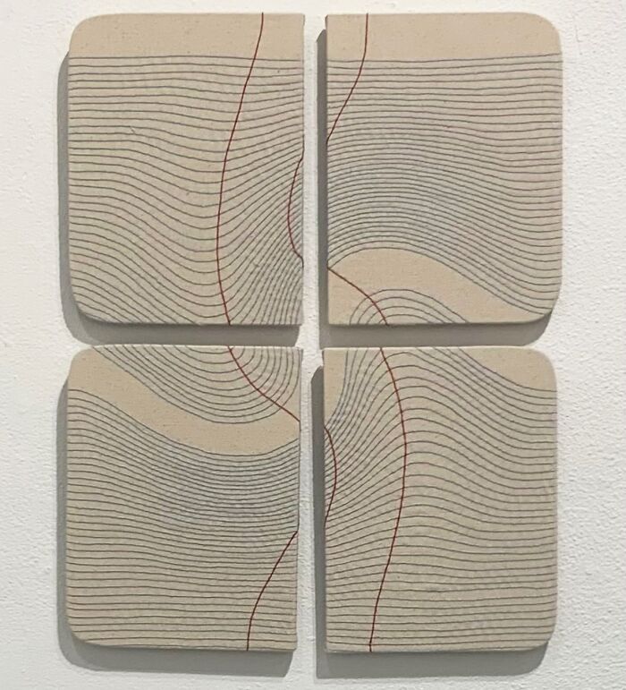 Embroidery art resembling notebook pages with curving lines on fabric, artistically divided into four sections.