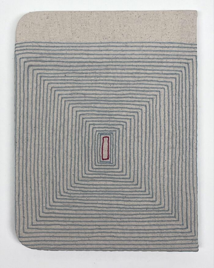 Fabric embroidered to look like notebook pages, featuring concentric lines with a red rectangle at the center.