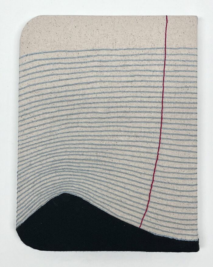 Embroidery art resembling a notebook page with lined fabric and red vertical stitching.