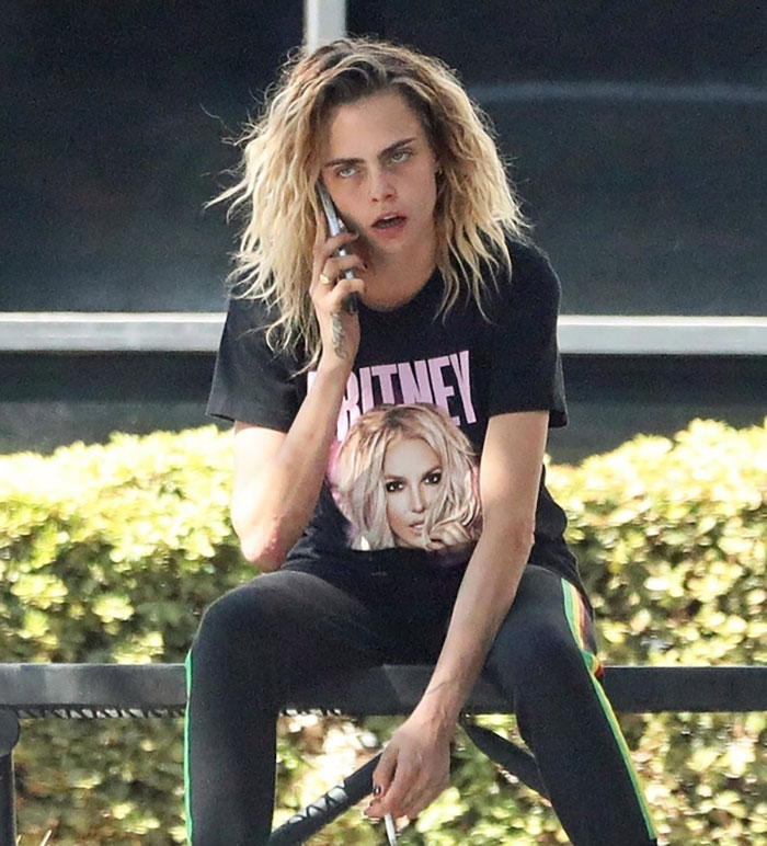 Person with dramatic transformation at Coachella, wearing a black Britney t-shirt, talking on the phone. Person with dramatic transformation at Coachella, wearing a black Britney t-shirt, talking on the phone.