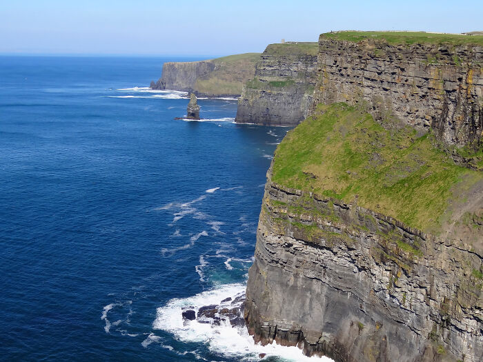 Coastal vistas showcasing towering cliffs and deep blue ocean under a clear sky.