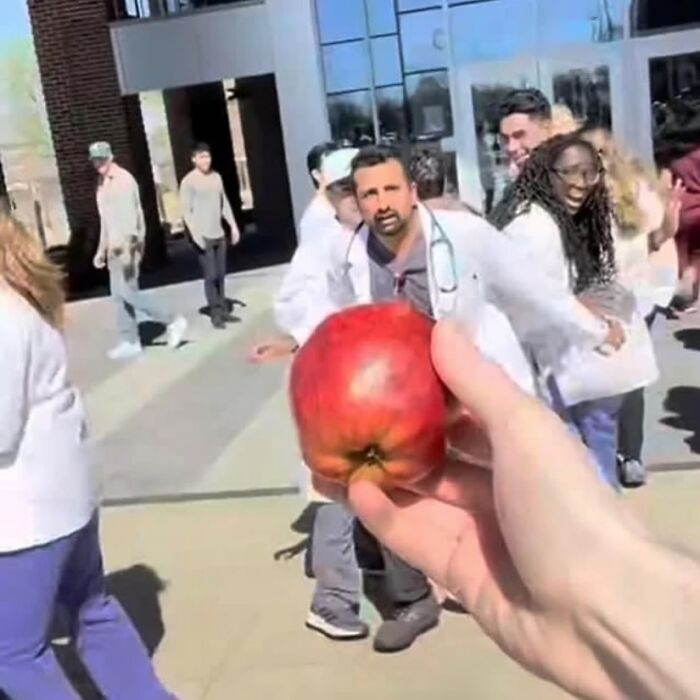Person holding an apple as a group of people in lab coats run toward them, creating a random cursed image. Person holding an apple as a group of people in lab coats run toward them, creating a random cursed image.