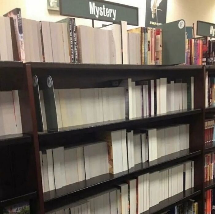 Books on a shelf with blank spines labeled "Mystery," creating a cursed visual effect. Books on a shelf with blank spines labeled "Mystery," creating a cursed visual effect.