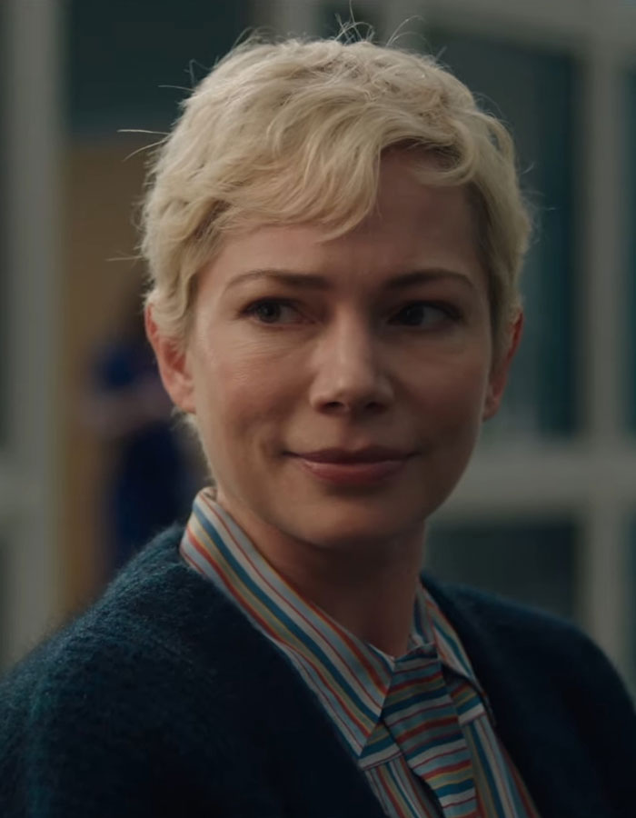 Short-haired woman smiling gently, wearing a striped shirt and dark sweater, indoors. Short-haired woman smiling gently, wearing a striped shirt and dark sweater, indoors.