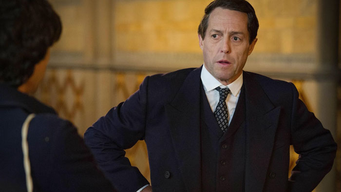 Hugh Grant speaking passionately indoors, wearing a suit, expressing views on elite schools' rules. Hugh Grant speaking passionately indoors, wearing a suit, expressing views on elite schools' rules.