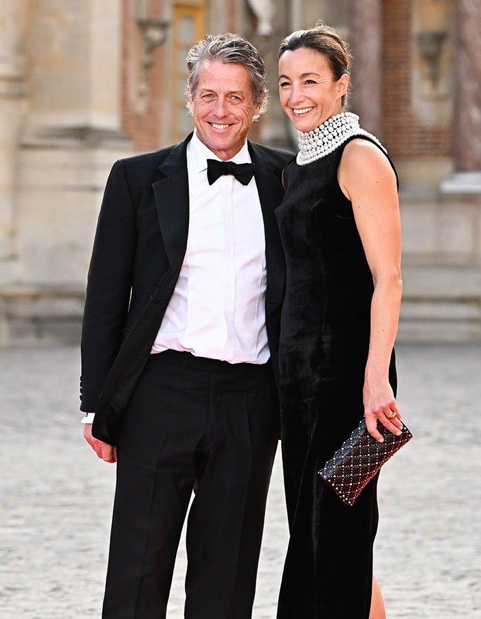 Man and woman in formal wear at an outdoor event; main SEO keyword: Hugh Grant. Man and woman in formal wear at an outdoor event; main SEO keyword: Hugh Grant.