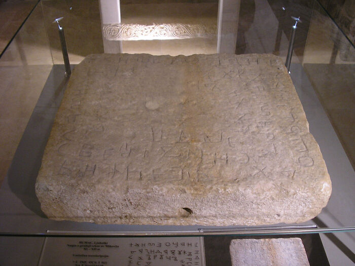 Ancient stone slab with engraved text, showcasing one of the world’s oldest written texts in a museum display.