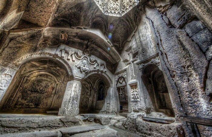 Eerie underground city with intricate rock carvings and arches.