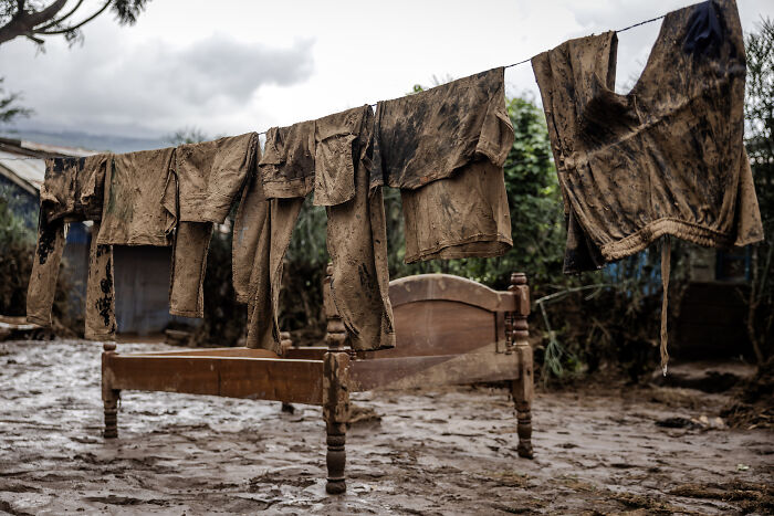 Muddy clothes hanging above a wooden bed in a flood zone, reflecting powerful imagery at Istanbul Photo Awards 2025.