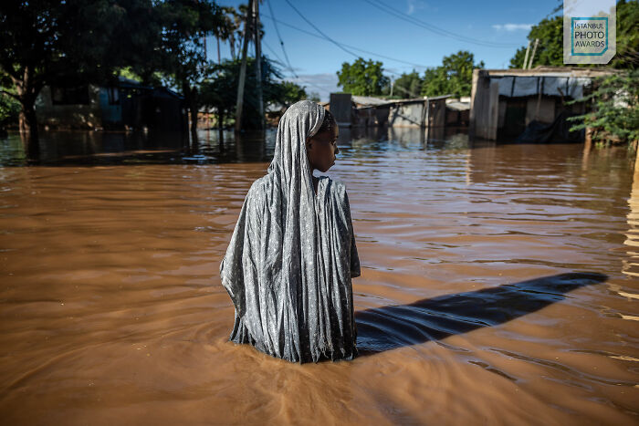 Person wading through floodwaters in a rural area, illustrating a powerful moment from Istanbul Photo Awards 2025.