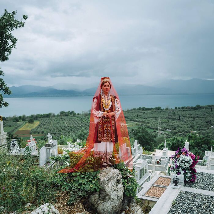 Woman in traditional clothing at a graveyard, with a scenic view, featured in Istanbul Photo Awards 2025.