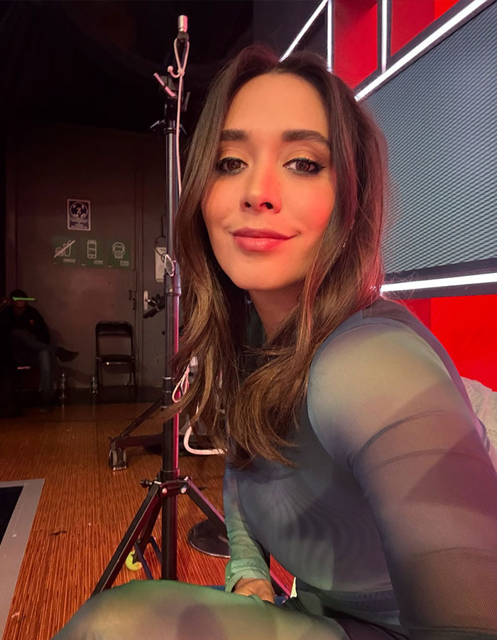 Female reporter on set, smiling, amidst outrage after live TV incident. Female reporter on set, smiling, amidst outrage after live TV incident.