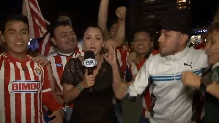 Female reporter surrounded by soccer fans on live TV. Female reporter surrounded by soccer fans on live TV.