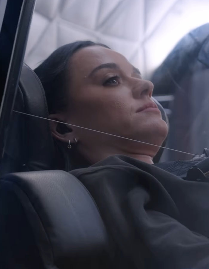 A person reclining in a space capsule seat, appearing calm and reflective after a space trip. A person reclining in a space capsule seat, appearing calm and reflective after a space trip.