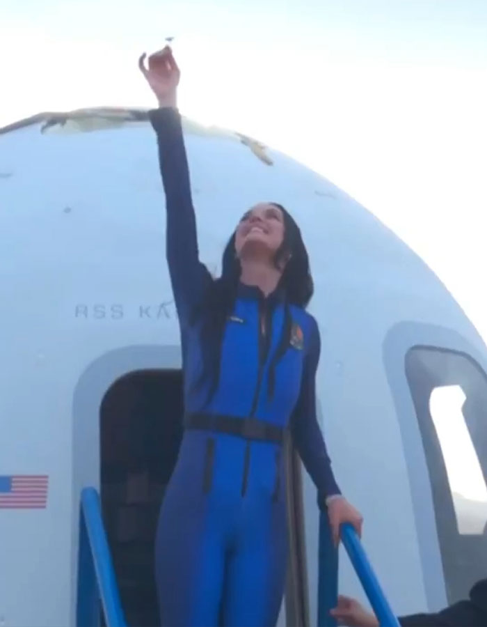 Person in space suit exits spacecraft, raising hand skyward, after a brief space trip. Person in space suit exits spacecraft, raising hand skyward, after a brief space trip.