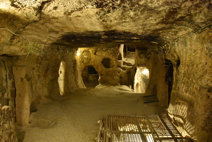 Underground city tunnel with rock walls and warm lighting, showcasing eerie architecture below ground.